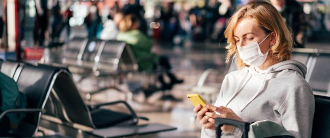 Woman sitting at the airport and using her phone