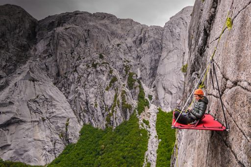 Woman sitting on the board hanging from a cliff