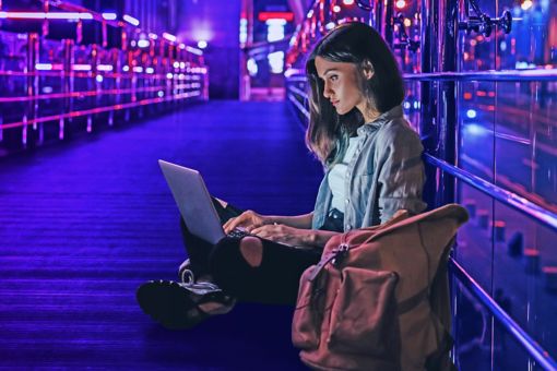 vrouw werkt op laptop met verlichte stad op de achtergrond