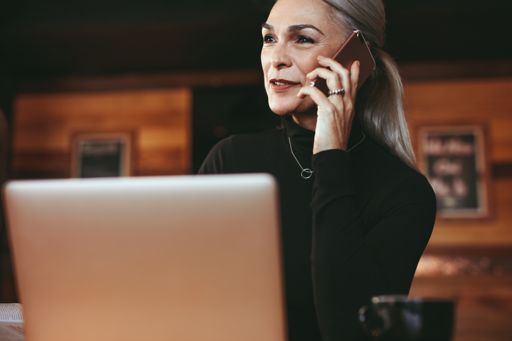 Woman speaking on phone while working on laptop