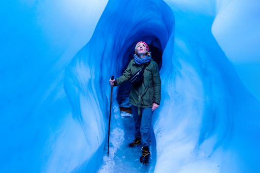Woman standing in an ice cave looking up to the light
