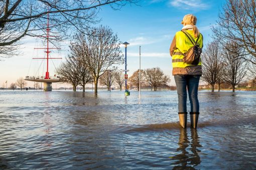 Femme en bottes de pluie debout dans un parc inondé