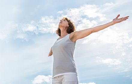 Woman standing spreading her arms looking towards the sky