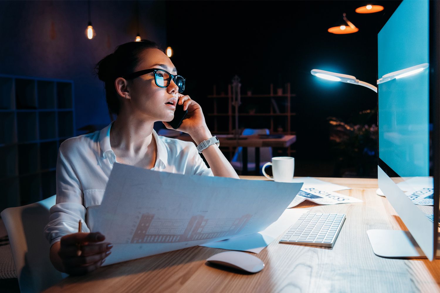 Woman talking on the phone and looking at her laptop while working
