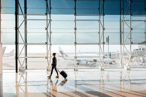 Une femme marche dans l’aéroport avec une valise à la main