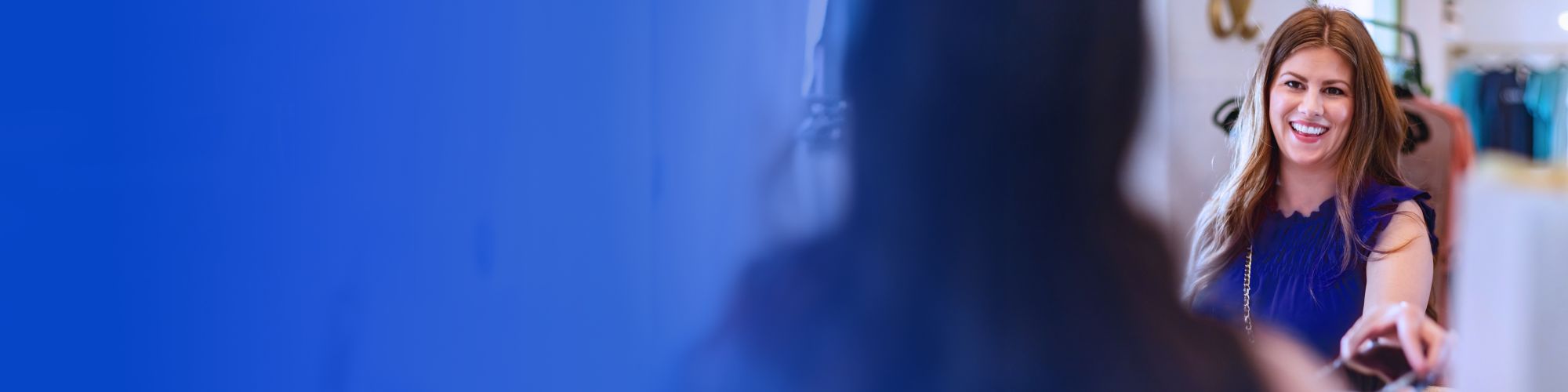 Woman in blue dress paying for clothes in retail store