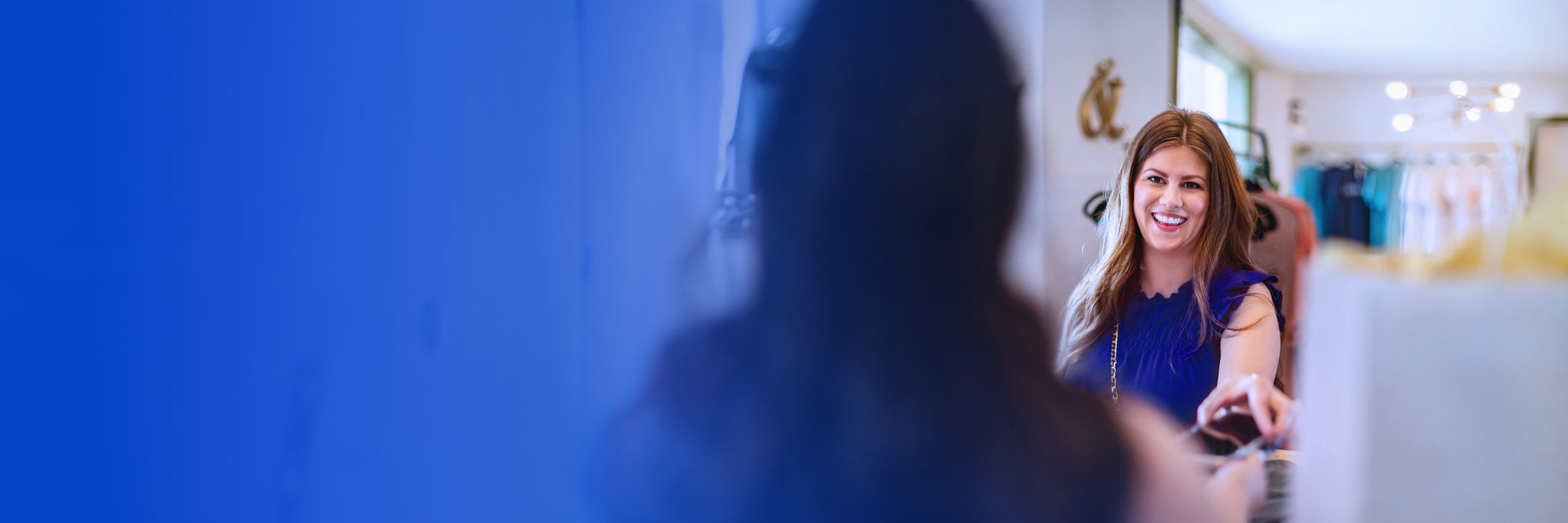 Woman in blue dress paying for clothes in retail store