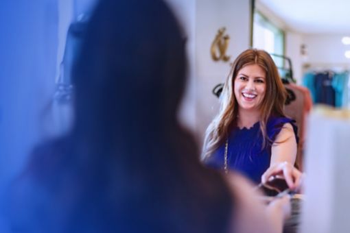 Woman in blue dress paying for clothes in retail store