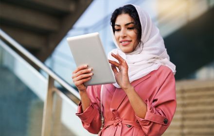 Young woman wearing headscarf using digital tablet outdoors