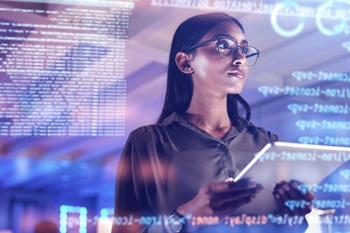 Woman with glasses looking at tablet and statistics