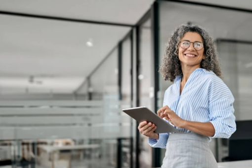 Woman with glasses smiling sideways holding tablet