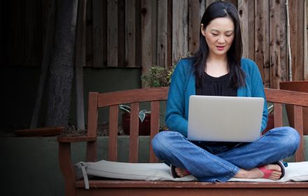 Women sitting on a bench working on her laptop