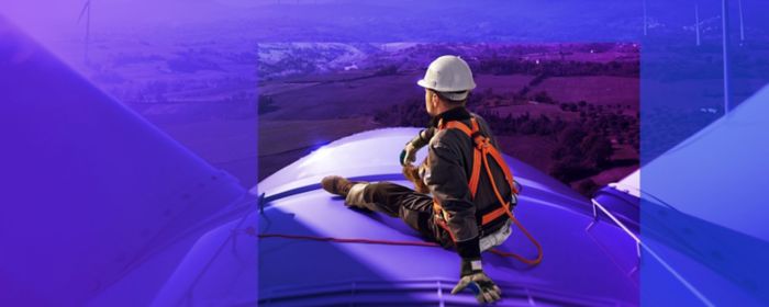 worker sitting on wind turbine looking at horizon