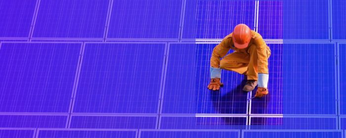 worker standing on solar panel fixing 