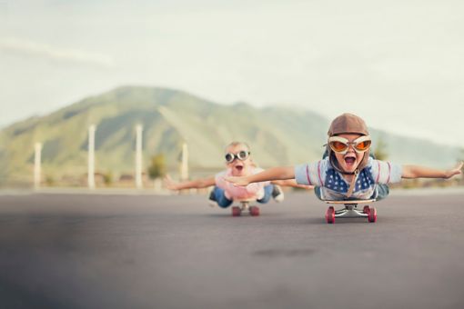 Young children on skateboards imagining that they are flying