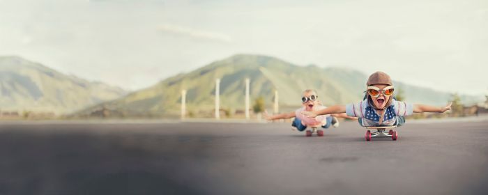 Young children on skateboards imagining that they are flying