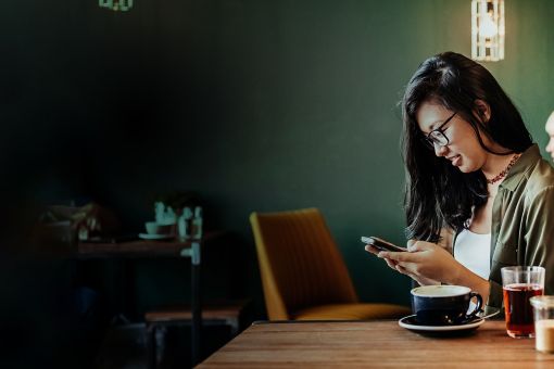 Young woman sitting in cafe using smartphone