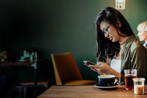 Young woman sitting in cafe using smartphone