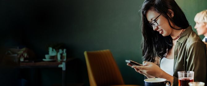 Young woman sitting in cafe using smartphone