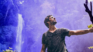 Pessoa a explorar a natureza com uma cascata no fundo