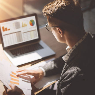 A man sitting behind a computer and holding papers