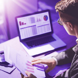 A man sitting behind a computer and holding papers