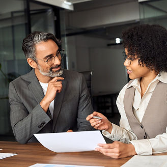 A man and woman are sitting next to each other while holding papers and talking