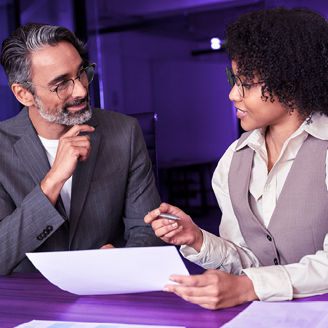 A man and woman are sitting next to each other while holding papers and talking