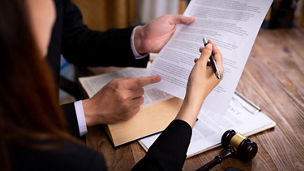 Two people are holding papers and pointing with a pen