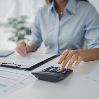 A woman is typing on a calculator