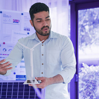 Man presenting infront of a white board with ESG content while holding a miniature of a wind turbine