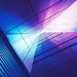 View through modern high rising skyscraper chimney upwards to blue sky with white clouds - abstract architecture detail background in turquoise teal blue to burgundy purple colors