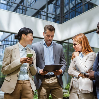 multiracial businesspeople review reports with business data charts in front company