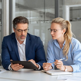 Two professional business people working together. Partners mature man and woman discussing project in office. Team leader explain trainee working process using tablet pc computer. Banner, copy space