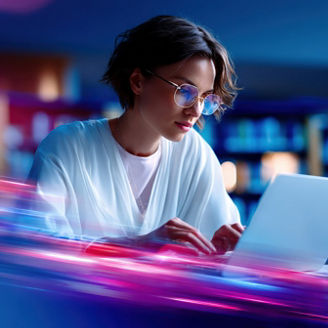 Young woman working on a laptop in a modern office environment with vibrant neon lights and blurred motion effects for technology and innovation themes.