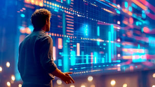 A person analyzes colorful data visualizations on a large screen, surrounded by ambient lighting, indicating a tech or business environment.