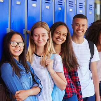 Teenage school kids smiling to camera in school corridor