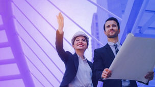 business or engineer asian woman and caucasian man with safety helmet and blueprint looking up at the building and checking their work in modern city, planning start up new project, successful concept