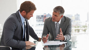 Dois homens conversando em uma mesa de escritório