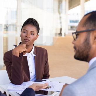 Multiethnic business partners discussing contract terms in outdoor cafe. African American business woman sitting at table and listening to her colleague. Partner meeting concept