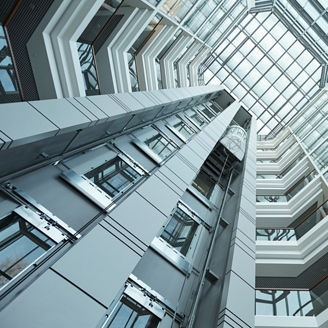 Part of interior of contemporary tall office building with moving elevator that can be used as background