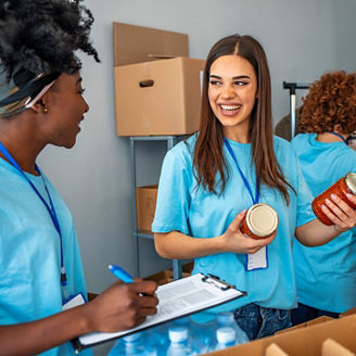 Group of people working in charitable foundation. Happy volunteer looking at donation box on a sunny day. Happy volunteer separating donations stuffs. Volunteers sort donations during food drive