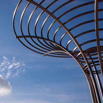 Conceptual abstract sculpture of metal chrome pipes against deep blue sky with a lonely cloud