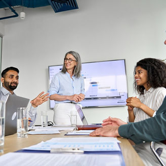 Diverse executive team people discussing company strategy at board meeting. Multicultural employees with senior leader listening indian manager brainstorming working sitting at table in office.