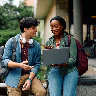 Happy African American student and her friend surfing the net on laptop at campus.