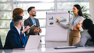Multiracial businesss people showing their colleagues diagrams and graphics on a business meeting. Talk about growth of the firm and statistics.