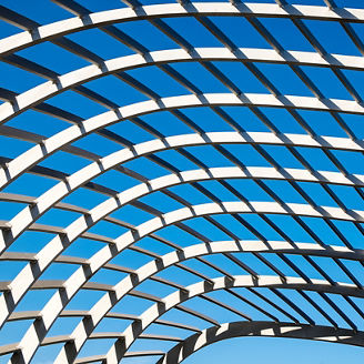 Overhead view of a geometric lattice with a pattern of arcs highlighted by sun and shade.