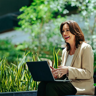 Woman working on laptop surrounded by greenery