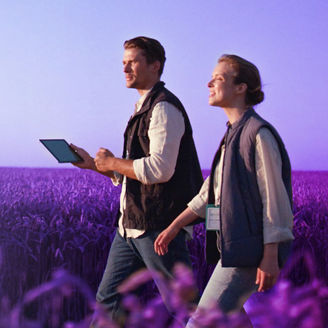 A man and a woman walking together in an open field, surrounded by grass and natural scenery
