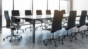 Modern boardroom with an empty conference table and chairs overlooking a city skyline